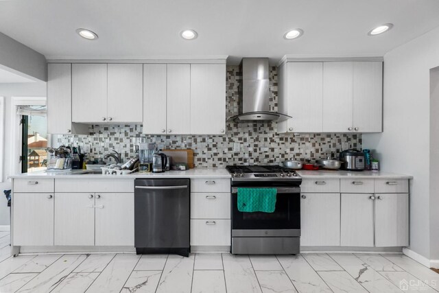 kitchen with sink, wall chimney exhaust hood, backsplash, white cabinets, and appliances with stainless steel finishes