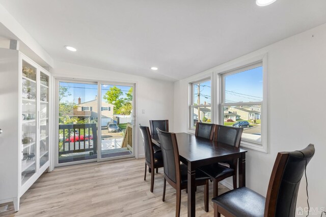 dining room with lofted ceiling, a healthy amount of sunlight, and light wood-type flooring