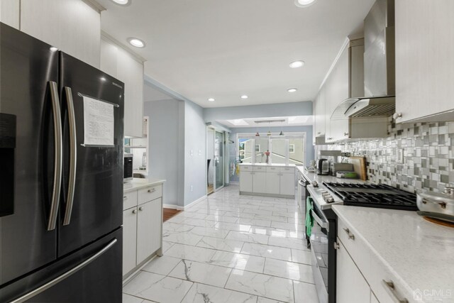 kitchen featuring white cabinets, wall chimney exhaust hood, decorative backsplash, and stainless steel appliances