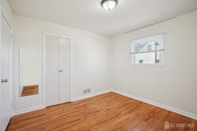 unfurnished bedroom with baseboards, light wood finished floors, and visible vents