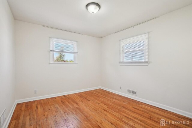 spare room featuring baseboards, visible vents, and light wood-style floors
