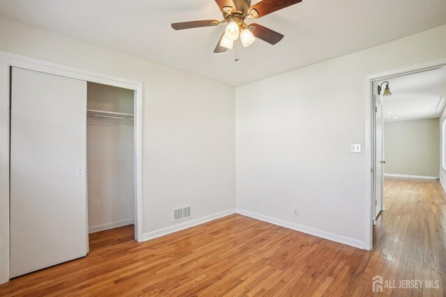 unfurnished bedroom with baseboards, a closet, light wood finished floors, and visible vents