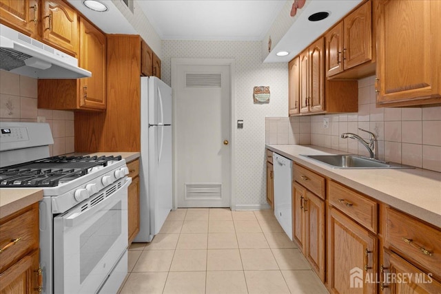 kitchen featuring a sink, under cabinet range hood, white appliances, light countertops, and wallpapered walls