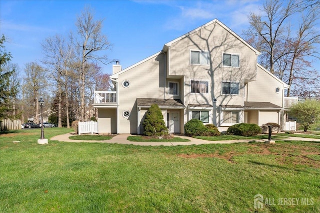 view of front of house featuring a chimney, a front lawn, and a balcony
