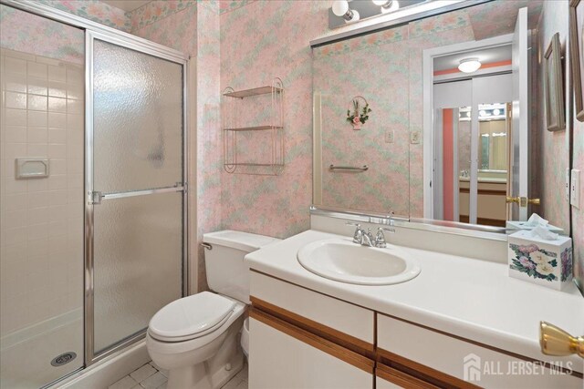 full bathroom with vanity, toilet, a stall shower, tile patterned flooring, and wallpapered walls