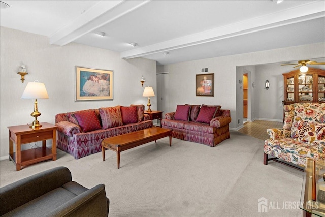 carpeted living area featuring beam ceiling, ceiling fan, and baseboards