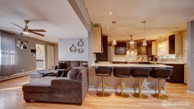 living room featuring light hardwood / wood-style flooring, ceiling fan, a baseboard heating unit, and sink