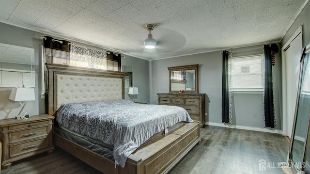 bedroom with ceiling fan, ornamental molding, and dark wood-type flooring