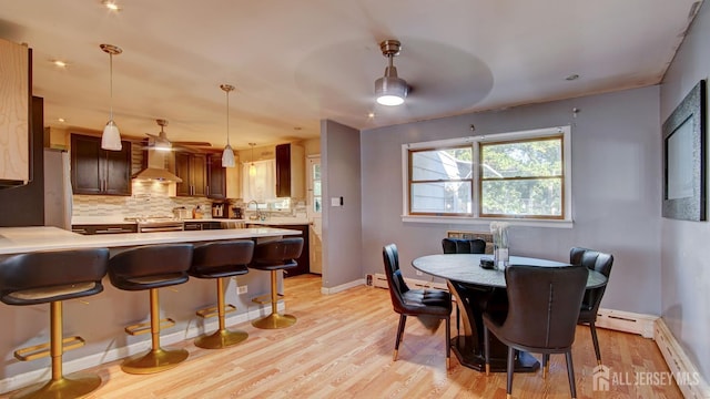 dining space featuring sink, light hardwood / wood-style floors, and a baseboard heating unit