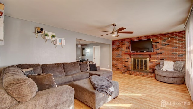 living room with ceiling fan, light wood-type flooring, and a brick fireplace