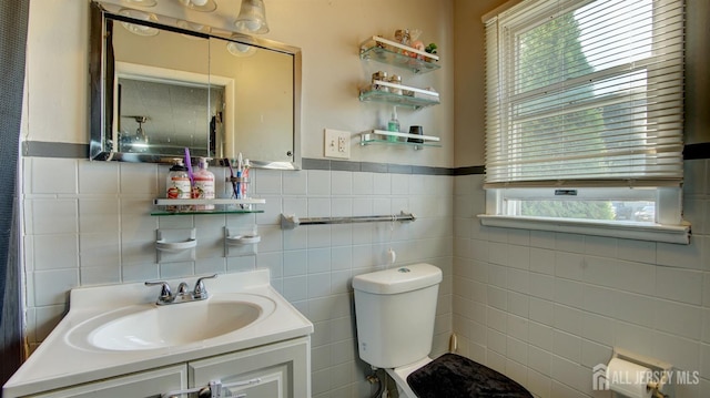 bathroom featuring vanity, toilet, a wealth of natural light, and tile walls