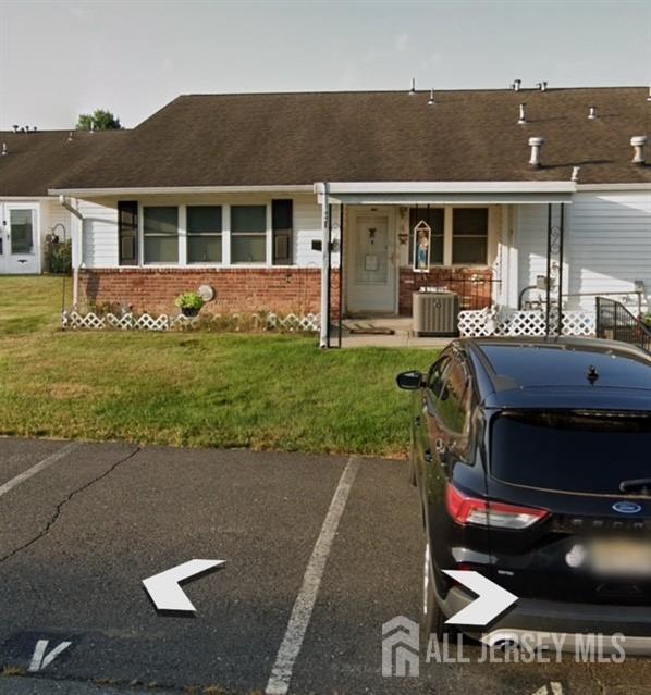 4 Montana Ct Unit D, Old Bridge, NJ 07747 - view of front of house featuring brick siding, covered porch, central air condition unit, a front yard, and uncovered parking