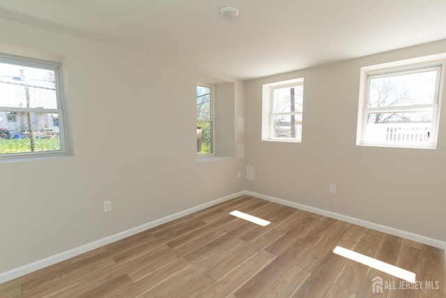spare room featuring baseboards and light wood-style flooring