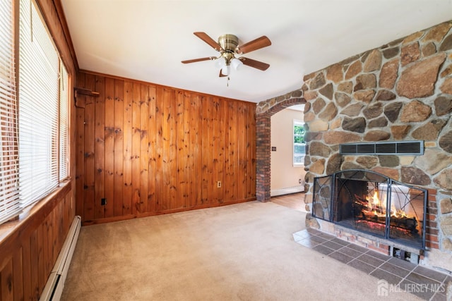 104 Old Matawan Rd, Old Bridge, NJ 08857 - unfurnished living room featuring a baseboard heating unit, wood walls, ceiling fan, a fireplace, and arched walkways