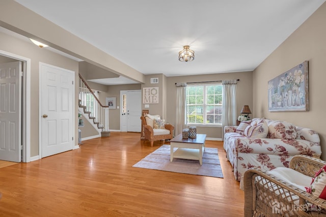 living room with light wood-type flooring, stairway, and baseboards