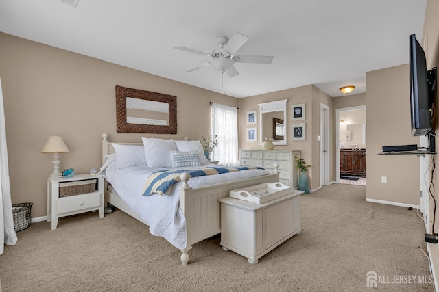 bedroom with light colored carpet, baseboards, ensuite bath, and a ceiling fan