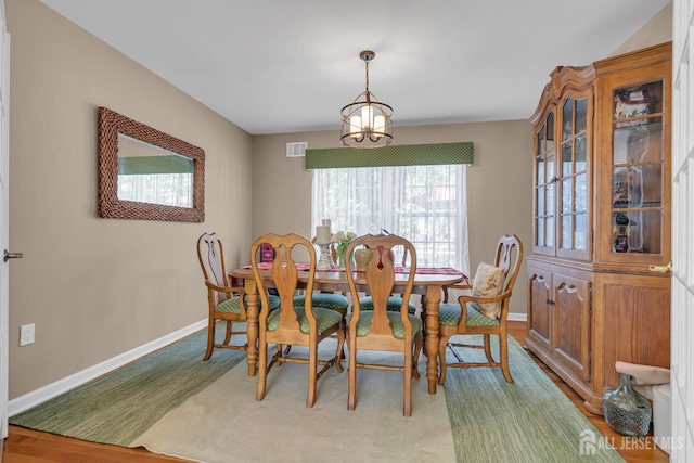dining space featuring baseboards, a chandelier, and wood finished floors