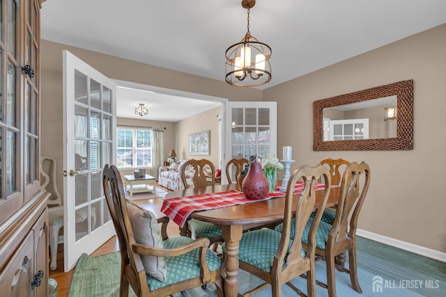 dining space with a chandelier, baseboards, and french doors