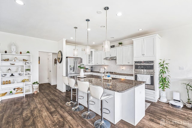 18 Larkspur Ln, Monroe, NJ 08831 - kitchen with appliances with stainless steel finishes, decorative backsplash, a breakfast bar area, under cabinet range hood, and glass insert cabinets