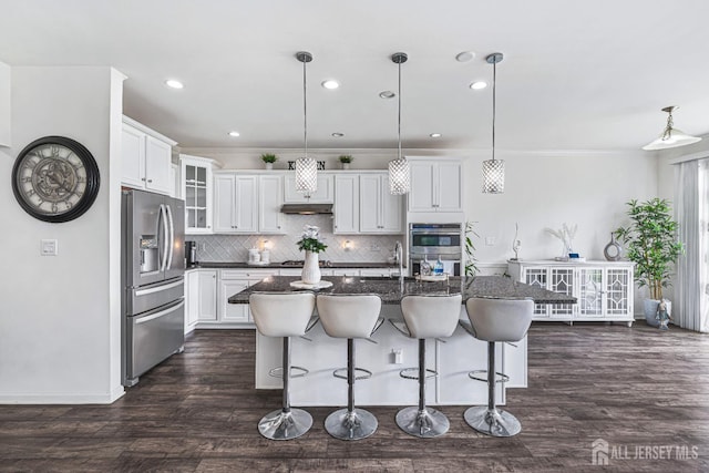 18 Larkspur Ln, Monroe, NJ 08831 - kitchen featuring appliances with stainless steel finishes, tasteful backsplash, a breakfast bar area, dark wood finished floors, and a center island with sink