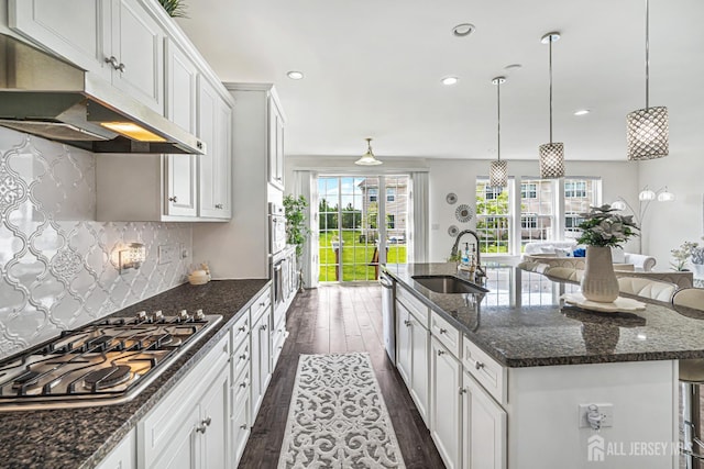 18 Larkspur Ln, Monroe, NJ 08831 - kitchen featuring under cabinet range hood, stainless steel gas stovetop, dark wood-style floors, a center island with sink, and backsplash