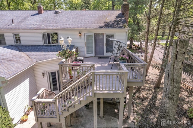 rear view of property featuring a chimney, roof with shingles, stairway, and a deck