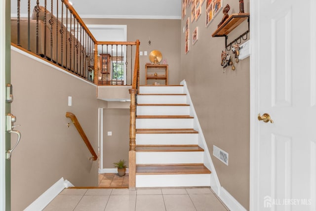 staircase featuring tile patterned floors, baseboards, and crown molding