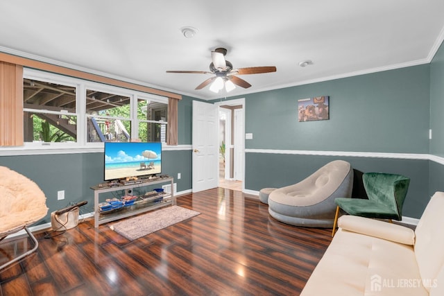 living area with wood finished floors, ornamental molding, baseboards, and ceiling fan