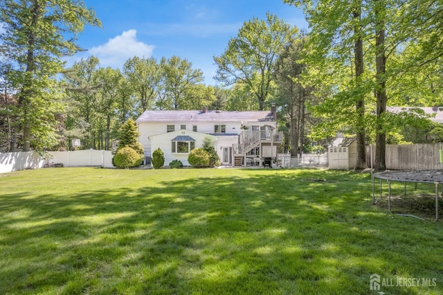 back of property with a storage shed, stairway, a trampoline, an outbuilding, and a chimney