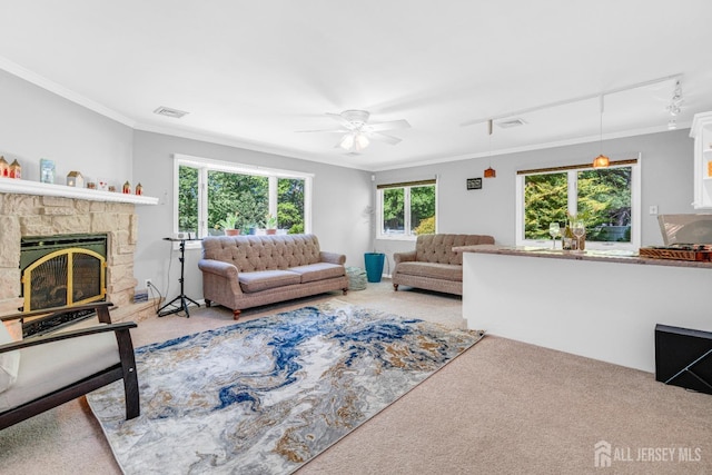 living area featuring carpet, crown molding, ceiling fan, and a stone fireplace