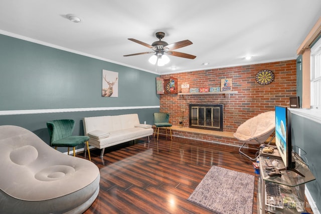 living room with wood finished floors, crown molding, a brick fireplace, ceiling fan, and brick wall
