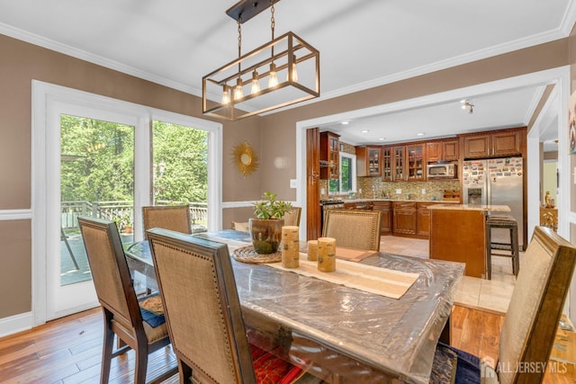dining space with a chandelier, ornamental molding, and light wood-style floors