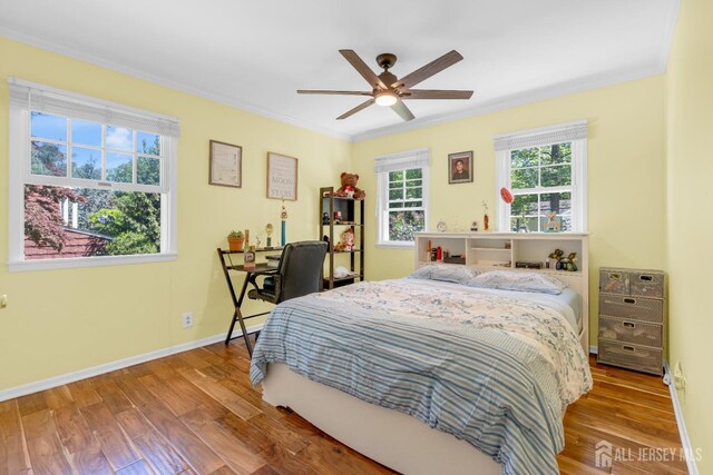 bedroom with crown molding, wood finished floors, baseboards, and ceiling fan