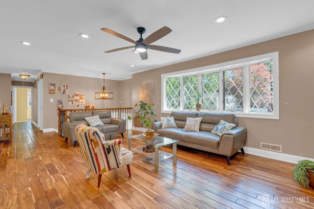 living area with light wood-type flooring, ceiling fan, ornamental molding, recessed lighting, and baseboards