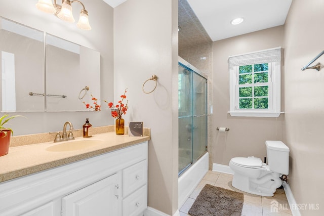 full bath with tile patterned flooring, toilet, vanity, baseboards, and bath / shower combo with glass door