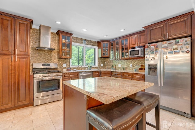kitchen featuring stainless steel appliances, wall chimney exhaust hood, light tile patterned floors, light stone counters, and recessed lighting