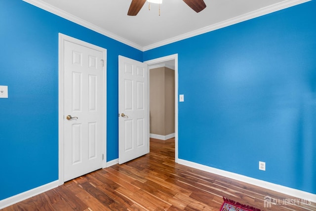 unfurnished bedroom with baseboards, wood finished floors, ceiling fan, and ornamental molding