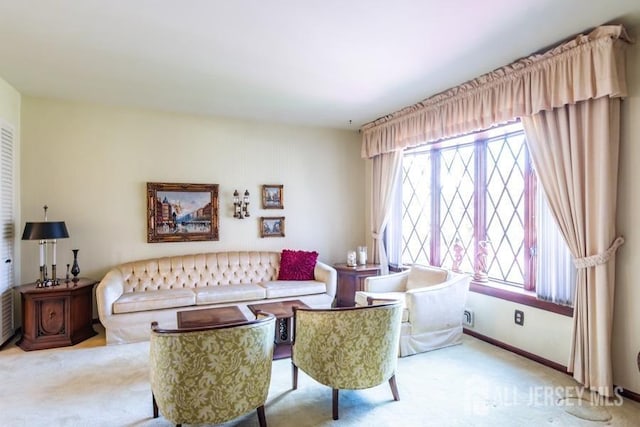 carpeted living area with healthy amount of natural light and baseboards