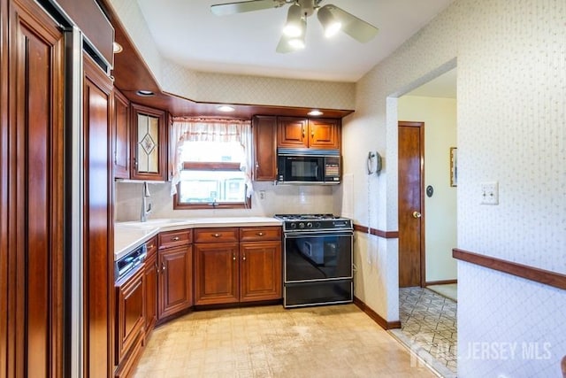 kitchen featuring black appliances, a sink, wallpapered walls, light countertops, and light flooring