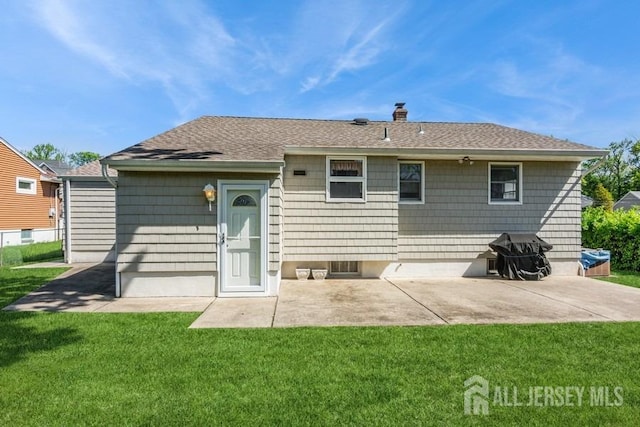 back of property featuring a yard, a patio, a chimney, and a shingled roof