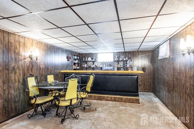 indoor dry bar featuring wood walls and a drop ceiling