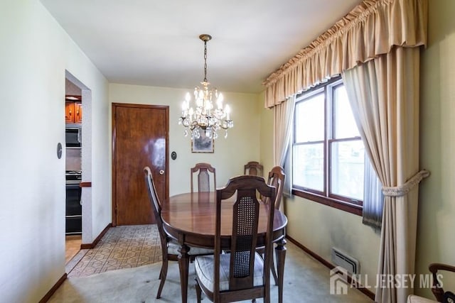 dining area featuring a chandelier, baseboards, and light colored carpet