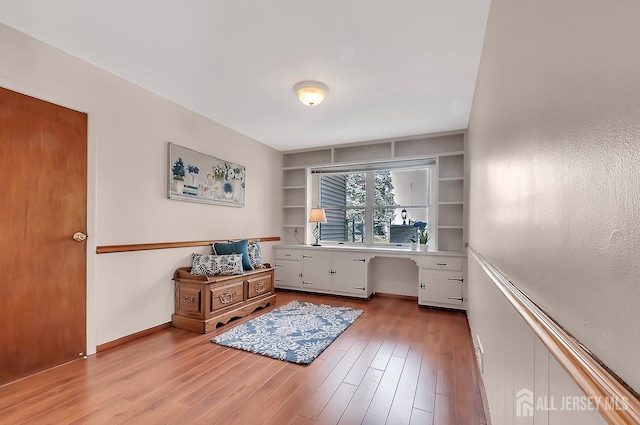 office area with light wood-style floors and built in shelves