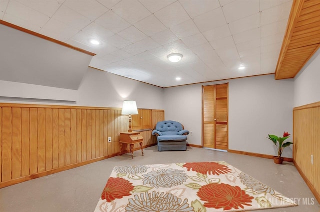 living area featuring baseboards, finished concrete flooring, and wainscoting