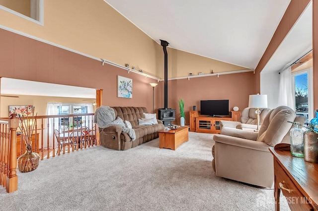 carpeted living room with a wood stove, healthy amount of natural light, and vaulted ceiling