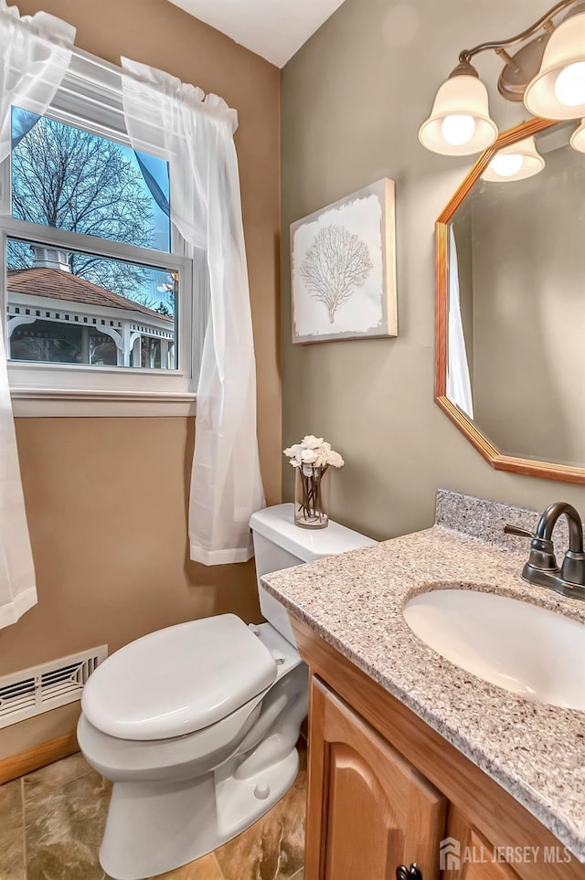 half bath featuring toilet, vanity, and visible vents
