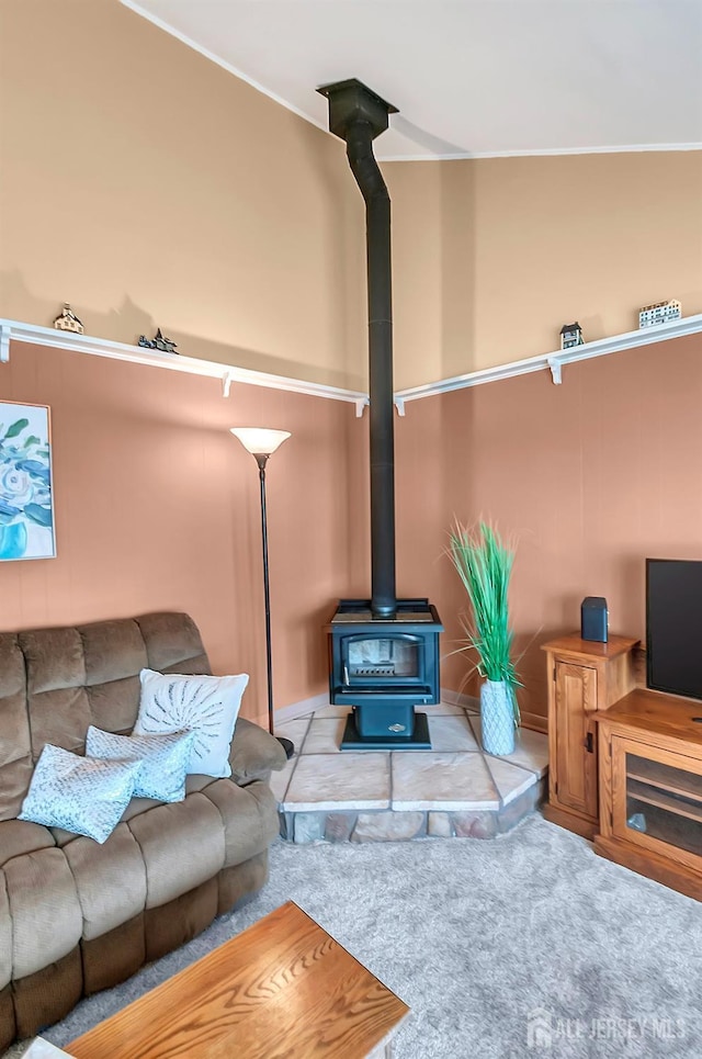 carpeted living area featuring a wood stove and ornamental molding