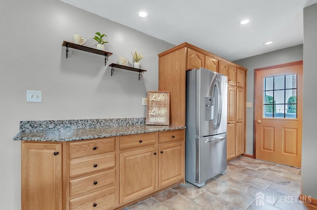kitchen with stainless steel fridge, open shelves, light stone counters, stone finish flooring, and recessed lighting
