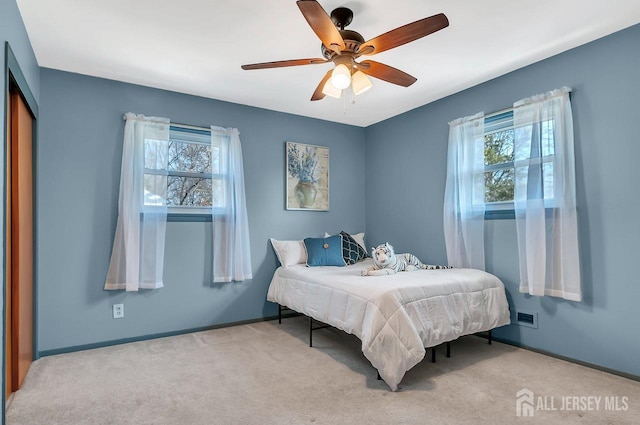 carpeted bedroom with baseboards, multiple windows, and a ceiling fan