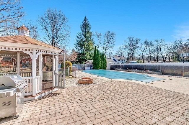 view of pool featuring an outdoor fire pit, a gazebo, a patio, a fenced backyard, and area for grilling